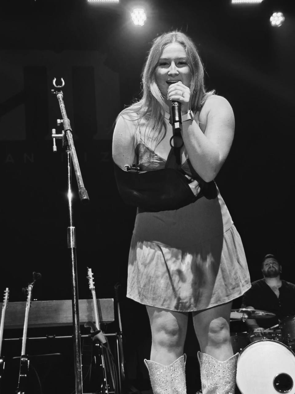 Briella Steiner singing into a handheld microphone onstage